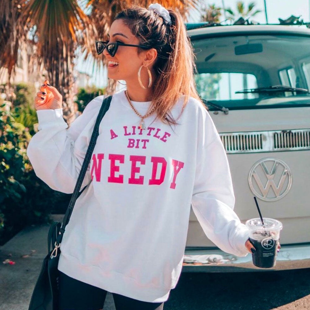 A Little Bit Needy Sweatshirt - Femfetti - A white graphic crewneck sweatshirt with the phrase &quot;A Little Bit Needy&quot; in pink text.