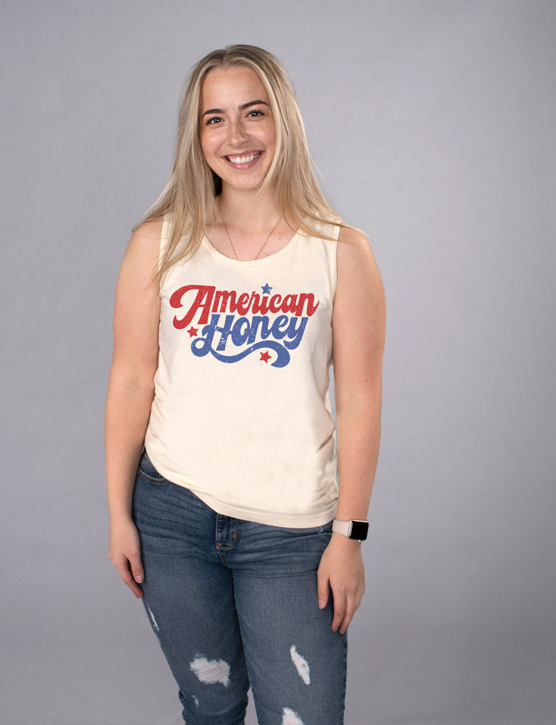 American Honey Tank Top - Femfetti - An ivory color unisex fit graphic tank top featuring the phrase &quot;American Honey&quot; in red and blue retro text.