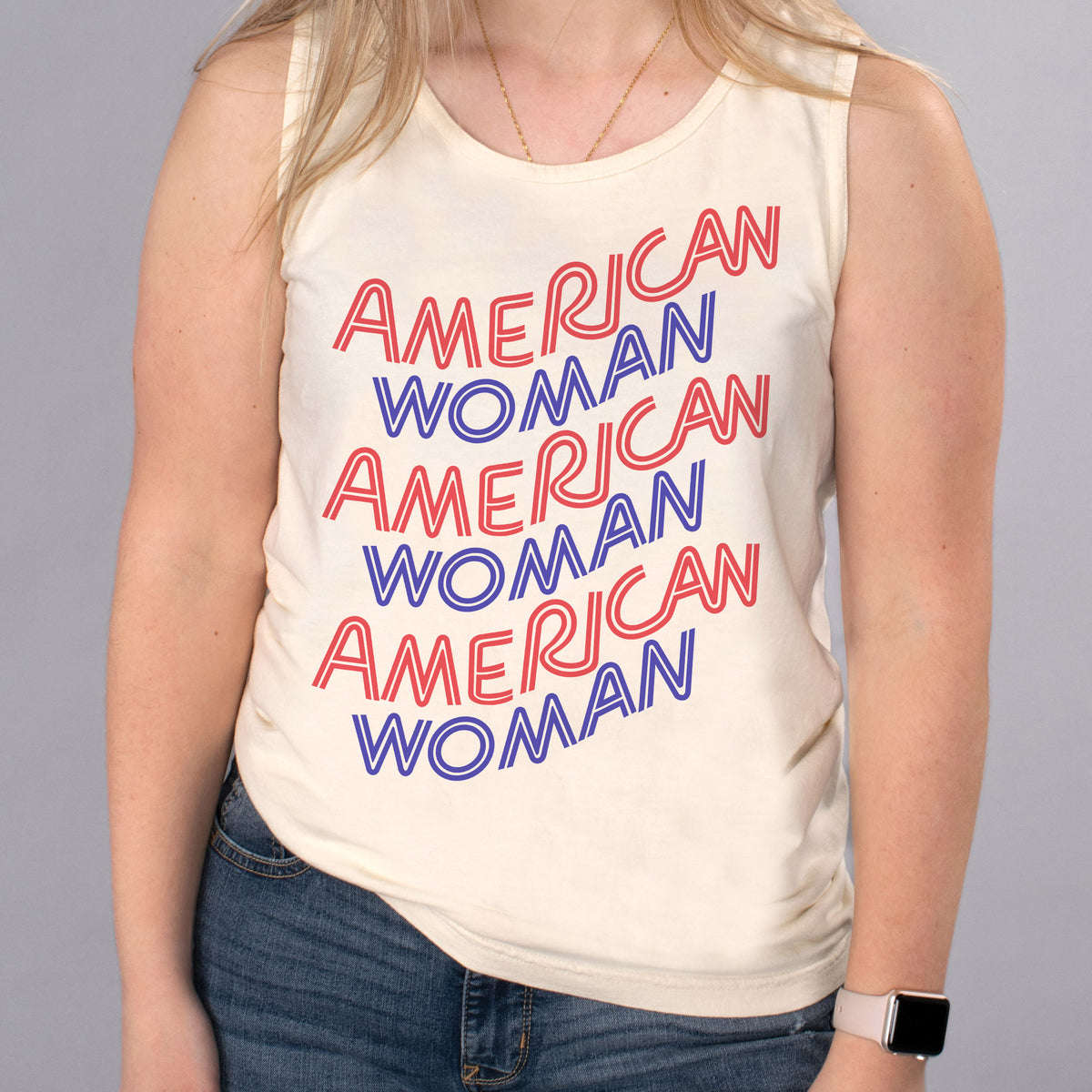 American Woman Tank Top - Femfetti - An ivory color unisex fit graphic tank top featuring the phrase &quot;American Woman&quot; in red and blue retro style text.