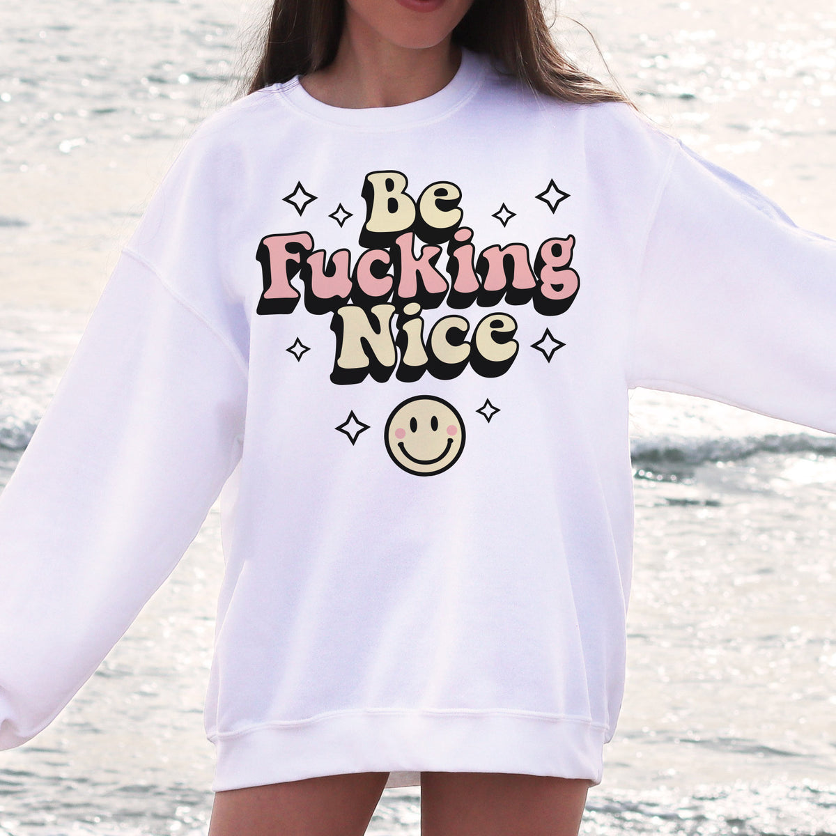 Be Fucking Nice Sweatshirt - Femfetti - A white oversized unisex fit graphic sweatshirt featuring the phrase &quot;Be Fucking Nice&quot; with a smiley face graphic.