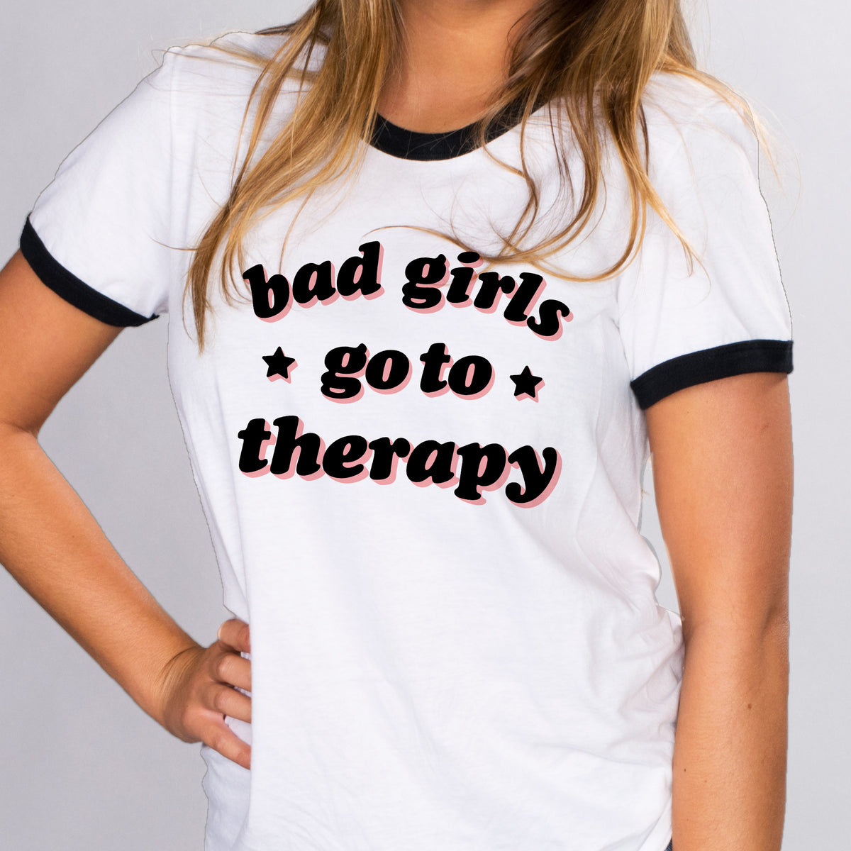 Bad Girls Go To Therapy Ringer Tee - Femfetti - A white and black unisex fit ringer tee shirt featuring the phrase &quot;bad girls go to therapy&quot; in black and pink font.
