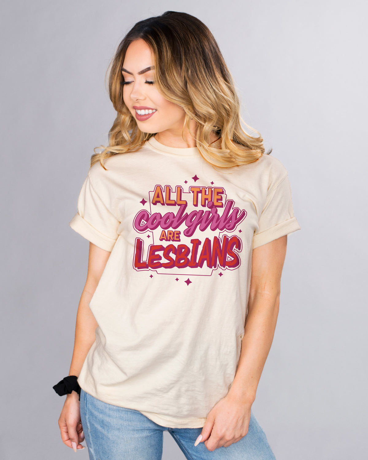 All The Cool Girls Are Lesbians - Femfetti - A natural color unisex fit graphic tee featuring the phrase &quot;all the cool girls are lesbians&quot; in the lesbian pride colors of orange purple and red.