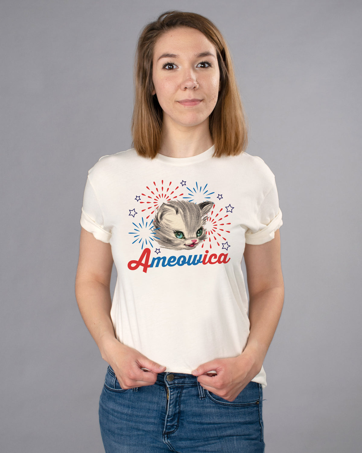Ameowica Shirt - Femfetti - A natural color unisex fit graphic tee featuring the word &quot;Ameowica&quot; in red and blue with the image of a cat and fireworks.