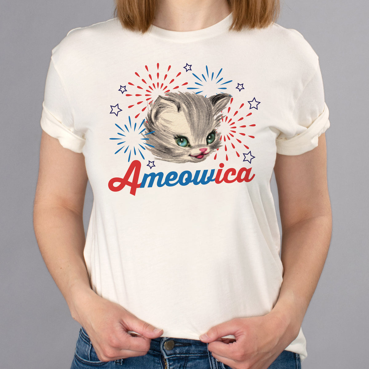 Ameowica Shirt - Femfetti - A natural color unisex fit graphic tee featuring the word &quot;Ameowica&quot; in red and blue with the image of a cat and fireworks.