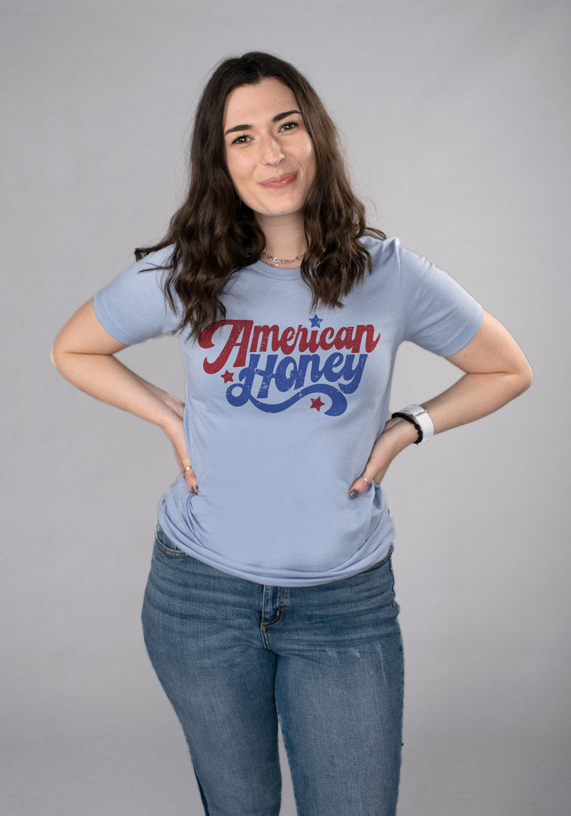 American Honey Shirt - Femfetti - A light blue unisex fit graphic tee featuring the phrase &quot;American Honey&quot; in red and blue retro text.